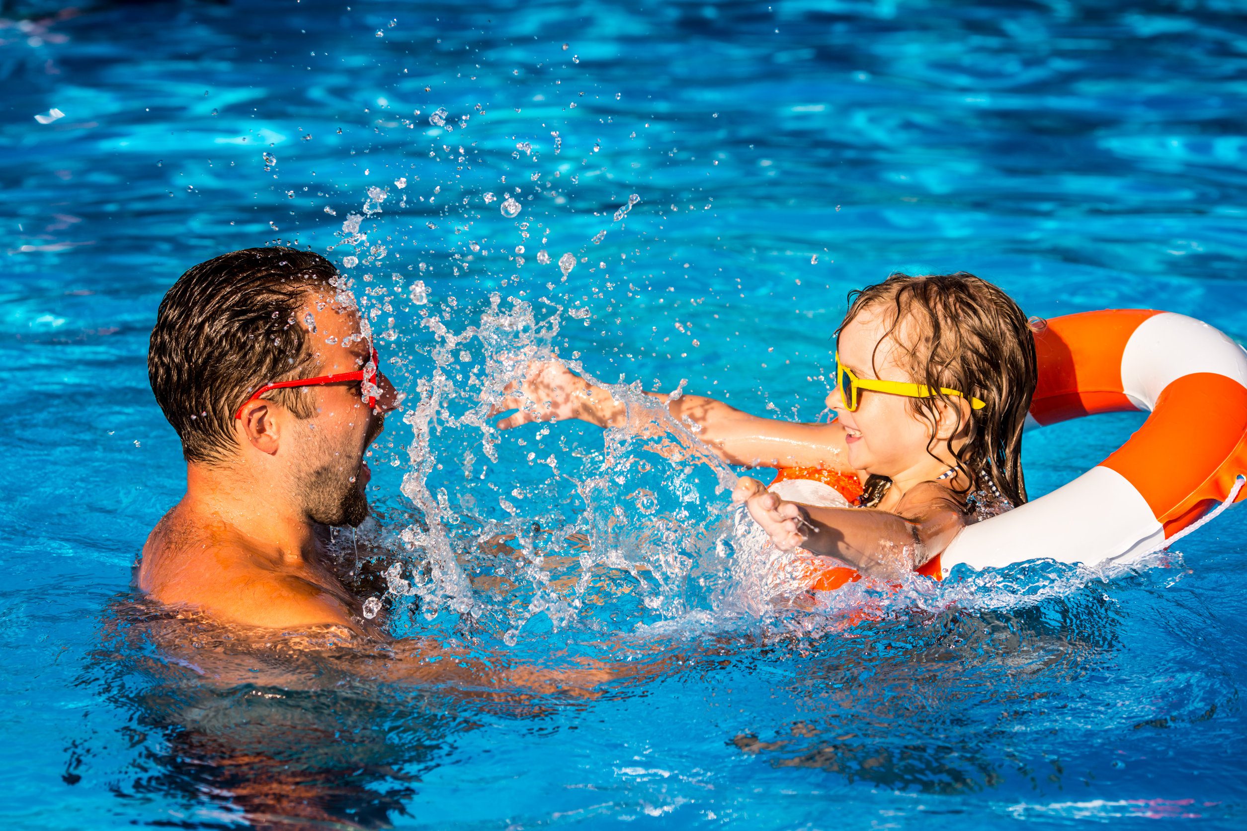 Child and father playing in swimming pool Child and father playing in swimming pool